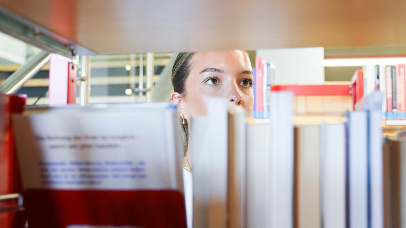 Frau blickt in das Bücherregal - Frontansicht